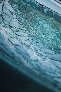 Arabanın ön camındaki kırık güvenlik camının detaylı görüntüsü. Kırık cam desenleri merkezi darbe noktasından yayılıyor..