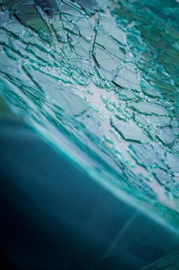 Arabanın ön camındaki kırık güvenlik camının detaylı görüntüsü. Kırık cam desenleri merkezi darbe noktasından yayılıyor..