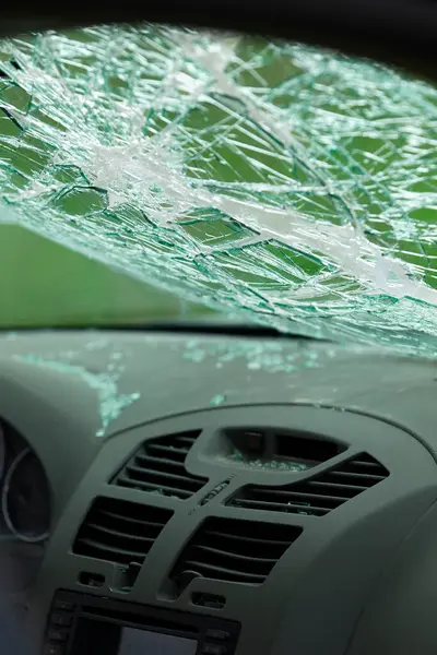 Parçalanmış ön camlı ve dağınık camlı arabanın iç manzarası. Torpido gözünün üstündeki güvenlik camında çatlaklar var..
