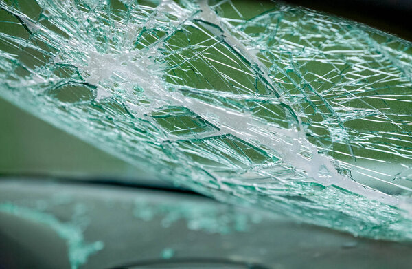 Fractured car windshield showing impact center and radiating lines. Broken safety glass with high detail and depth.