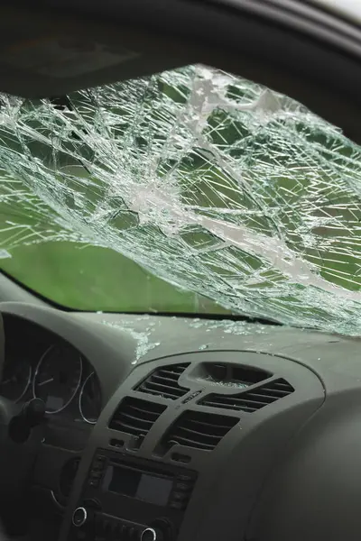 Ön camları kırılmış ve ön panelinde kırık camlar olan arabanın iç manzarası. Çarpışma hasarı güvenlik camında görülüyor..