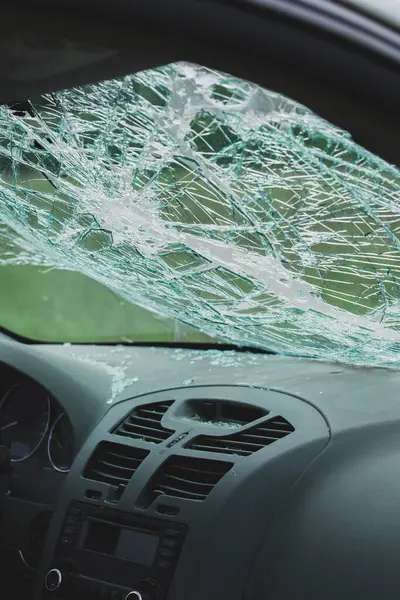 Ön camları kırılmış ve ön panelinde kırık camlar olan arabanın iç manzarası. Çarpışma hasarı güvenlik camında görülüyor..