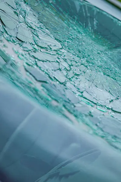 Kırık ön cam ve parlak çatlaklar. Hasarlı bir güvenlik camındaki örümcek ağı çatlaklarına yakın çekim.