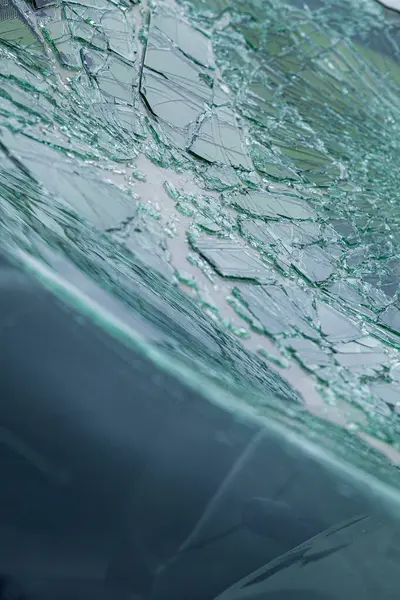 Arabanın ön camındaki kırık güvenlik camının detaylı görüntüsü. Kırık cam desenleri merkezi darbe noktasından yayılıyor..