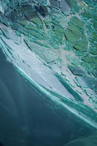 Arabanın ön camındaki kırık güvenlik camının detaylı görüntüsü. Kırık cam desenleri merkezi darbe noktasından yayılıyor..