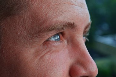 Yakışıklı bir adam yüzünü ve gözlerini başka yöne çeviriyor. Mavi gözler. Göz bakımı, göz muayenesi, lazer ameliyatı, lenslerin ve gözlüklerin reklamı, göz sağlığı kliniği hizmetleri konsepti