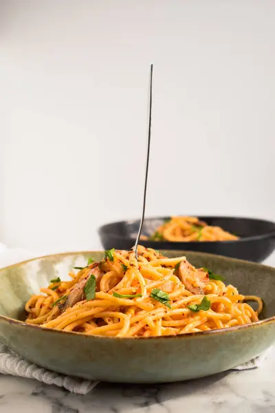 Spagetti ai Funghi Porcini - Porcini mantarlı İtalyan makarna yemeği, kırmızı biber, domates sosu ve maydanoz. Arka planda iki tabak makarna..