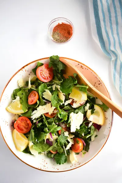 Domates yeşili yapraklı yeşil vegan salatası ve taze sebzeler. Beyaz bir masada en üstten görünüm.