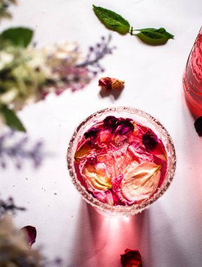 Gül çiçekleri ve açık gri masada fesleğen ile nefis ferahlatıcı bir içecek.