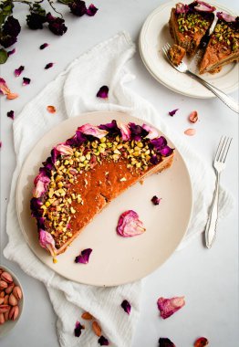 Kurutulmuş gül tomurcukları, şam fıstığı ve yenilebilir gül yapraklarıyla süslenmiş sünger pastası..