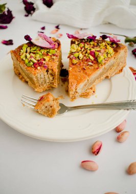 Kurutulmuş gül tomurcukları, şam fıstığı ve yenilebilir gül yapraklarıyla süslenmiş sünger pastası..