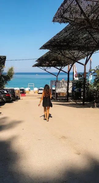 Siyah elbiseli bir kız sabah Lefkada, Yunanistan 'da sahile doğru yürüyor..