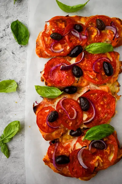 Peynirli bruschetta, domates, siyah zeytin ve kahverengi kabartma kağıdında fesleğen. İtalyan antipasti atıştırmalıkları..  