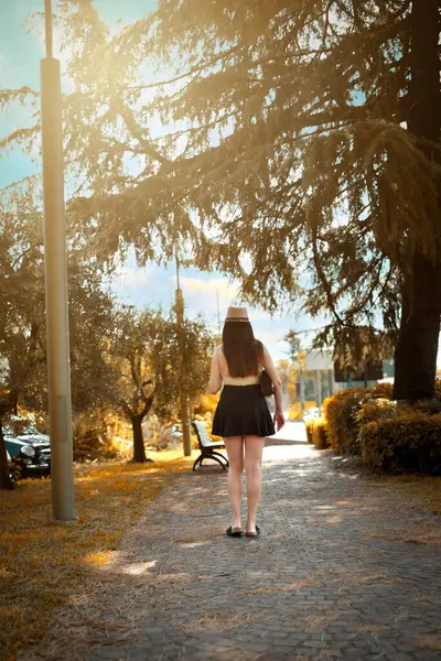 Zayıf bir kadın, arkadan görünüşlü, İtalya 'da bir yol parkında yürüyor.