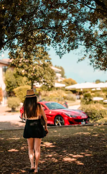 Güzel genç bir kadın bir yaz günü Ferrari 'nin arabasına doğru yürüyor.