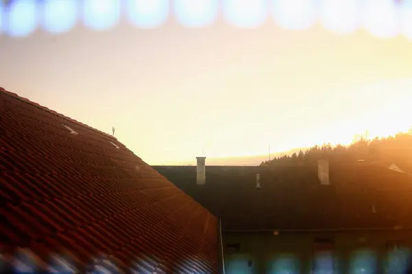 stock image This photograph captures the sunset over a neighborhood, with rooftops silhouetted against the glowing sky. The warm, golden hues of the sunset provide a beautiful contrast to the dark shapes of the rooftops, creating a picturesque and tranquil scene