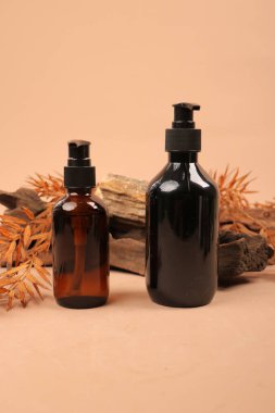 Kehribar ve Siyah Pompa Şişeleri Bej Arkaplanda Driftwood ve Sonbahar Aksanları