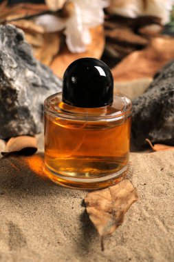 Arka planda bir kumun üzerindeki parfüm şişesi