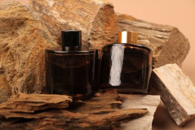 Kahverengi ve beyaz parfüm şişeleri ve ahşap arka planda kuru yapraklar..