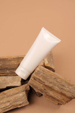 Beyaz krem tüpü ve bej arka planda kuru yaprak. Doğal ürün. en üstteki görünüm.