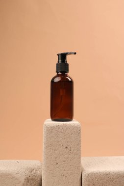 Turuncu arka planlı bej bir yüzey üzerinde beyaz bir banyo şişesinin dikey görüntüsü.