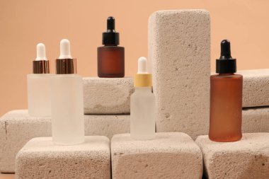 Doğal serumlu şişeler, serum ve kahverengi arka planda kuru yaprak.