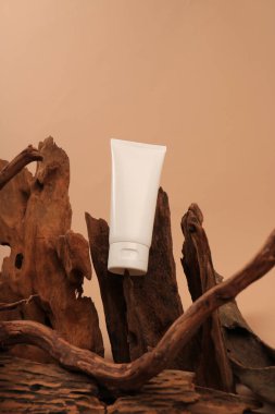 Kahverengi arka planda kozmetik ürünleri için krem içeren boş beyaz şişe..