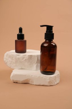 Şeffaf bir bardakta krema ve sabun şişesi..