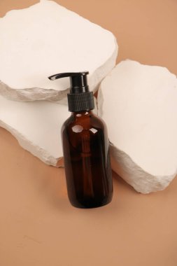 Kahverengi arka planda bir şişe ve bir bardak sabun. Vücut için doğal ürün.