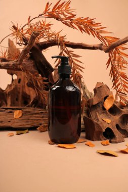 Kahverengi yağ şişesi ve kuru yapraklar ahşap masada, yakın plan. Metin için boşluk