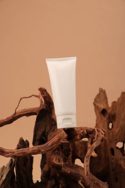 Kahverengi zemin üzerinde krem olan beyaz kozmetik tüp.
