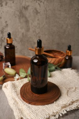 Masanın üzerinde okaliptüs dalları olan bir şişe temel yağ.