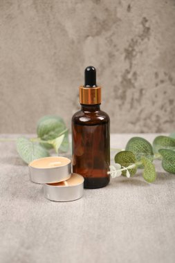 Gri arkaplanda kozmetik şişeler ve okaliptüs yaprakları, metin için boşluk