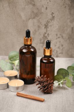 Gri arkaplanda gerekli yağ şişeleri ve dallarla kompozisyon