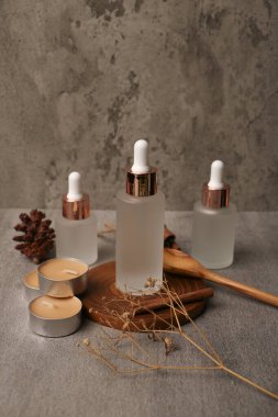 Doğal serum ve okaliptüs yapraklı kozmetik ürünleri gri masada.