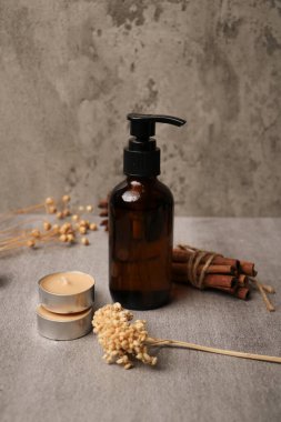 Yağ şişesi ve gri masada taze çiçekler.