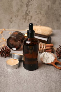 Kuru dalları ve gri arka planda kurumuş yaprakları olan gerekli yağ şişesi.