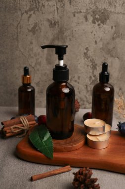 Gri masadaki doğal kozmetik ürünlerin şişeleriyle bezenmiş düz bir yapı. Metin için boşluk