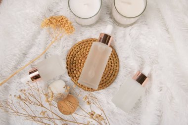 Beyaz arka planda bir şişe parfüm, çiçekler ve yapraklar.