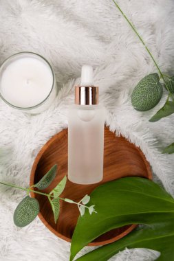 Cam şişeli ve beyaz yapraklı kozmetik şişesi.