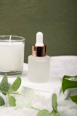 Renkli arka planda yaprakları ve çiçekleri olan bir şişe parfüm, yakın plan. Metin için boşluk