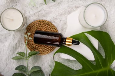 Doğal kozmetik şişesi, yeşil bir okaliptüs yaprağı ve hafif bir arka planı var. düz yatış, üst görünüm.