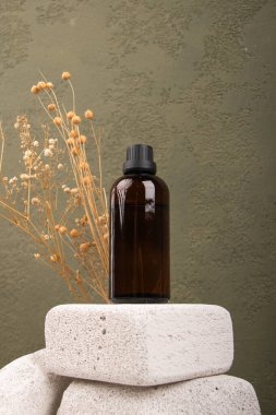 Gri desenli arkaplanda bir şişe ve bir bardak kuru yağ ve metin için yer var.