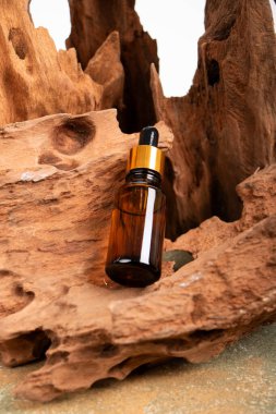 Plajda kahverengi kumlu cam yağ şişesi ve beyaz mermer arka planda bir kehribar şişesi.