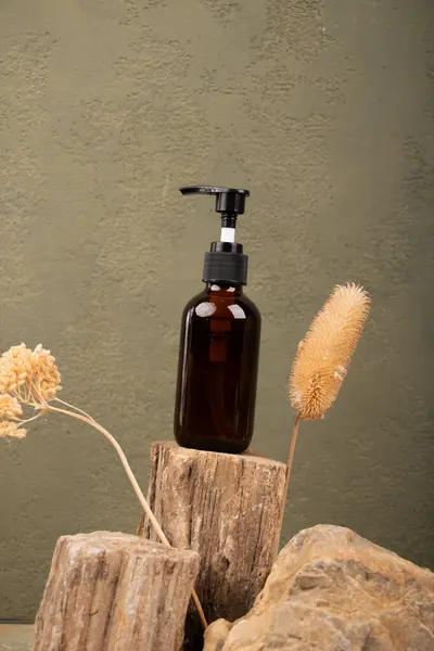 Kahverengi arka planda kuru çiçekli bir parfüm şişesi.