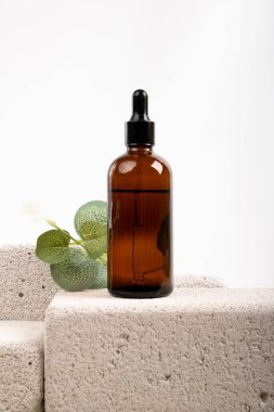 Gri arkaplanda boşluk olan bir şişe kozmetik yağı, yakın plan.