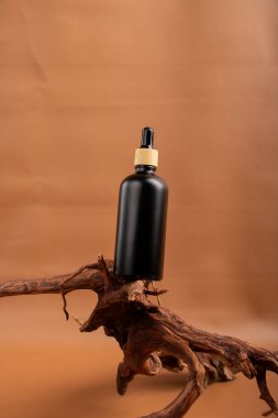 Bej arka planda kahverengi derili siyah bir serum şişesi. Doğal kozmetik ürünü. Boşluğu kopyala.