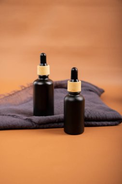 Siyah arka planda siyah kozmetik ürünleri olan iki siyah ve kahverengi şişe. Spa konsepti, deri ve vücut bakımı. Boşluğu kopyala.