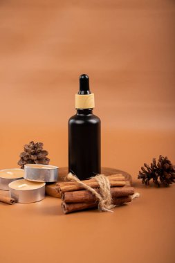 Kahverengi esmer esans yağı, kahverengi tarçın, tarçın çubukları ve beyaz arka planda anason yıldızları. Doğal Kozmetik.