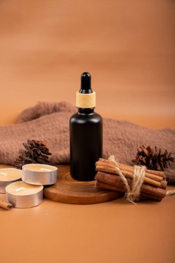 Kuru tarçın ve ahşap yüzeyinde tarçın çubukları olan gerekli yağ şişesi. Doğal kozmetik konsepti. Boşluğu kopyala.